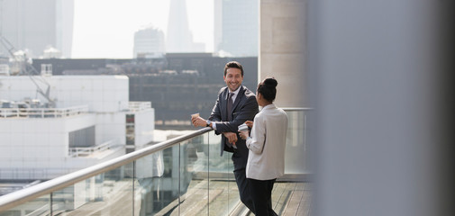 Business people talking on sunny, urban balcony