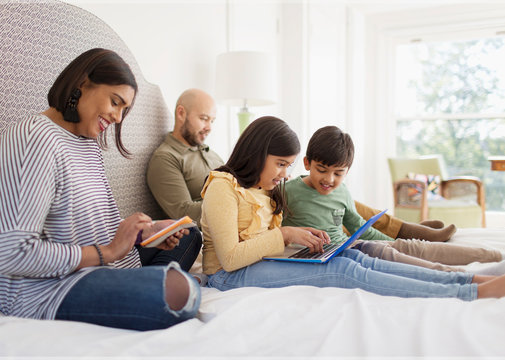 Family using technology on bed