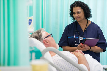 Doctor making rounds, talking with patient in hospital room