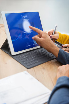 Couple paying bills, logging on to digital tablet with fingerprint