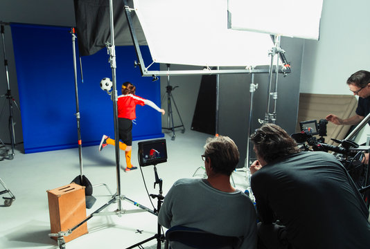 Photographers and teenage girl soccer player in studio photo shoot