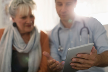 Male doctor showing digital tablet to patient