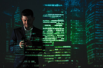 Double exposure businessman using smart phone against highrise lights at night