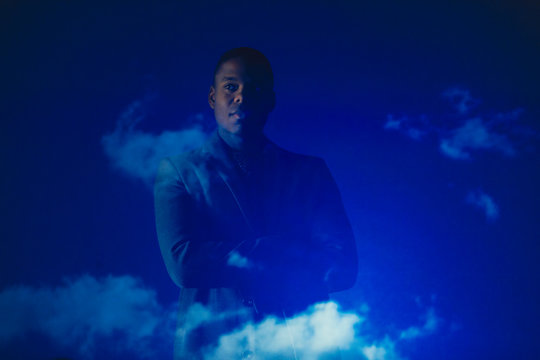 Double exposure thoughtful businessman against blue sky with clouds