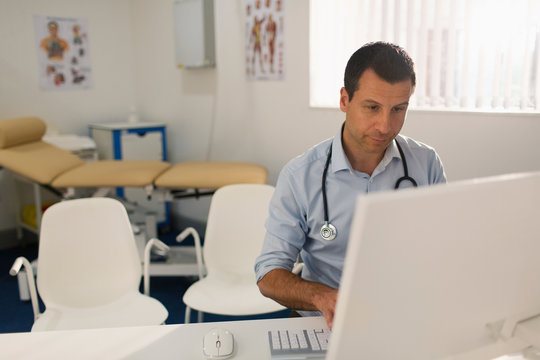 Male doctor working at computer in doctors office