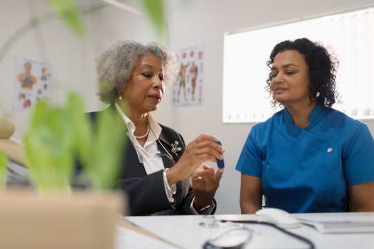 Female doctor teaching diabetic patient how to use glucometer in doctors office