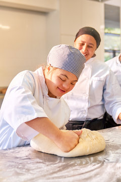 Young woman with Down Syndrome kneading dough in baking class
