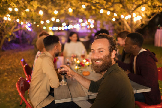 Portrait confident man drinking wine, enjoying dinner garden party