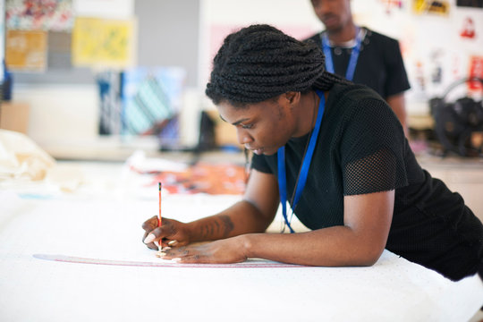 Focused female fashion designer drawing sewing pattern in studio