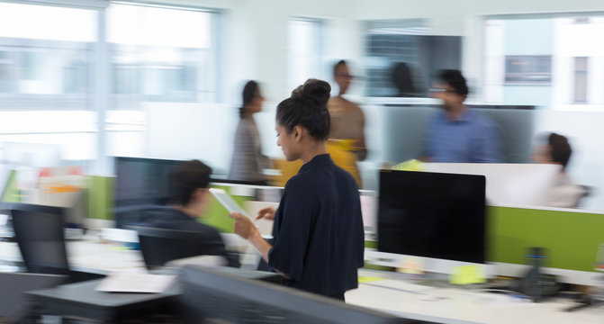 Businesswoman with digital tablet walking in office