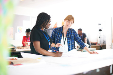 Female fashion designers drawing sewing pattern in studio