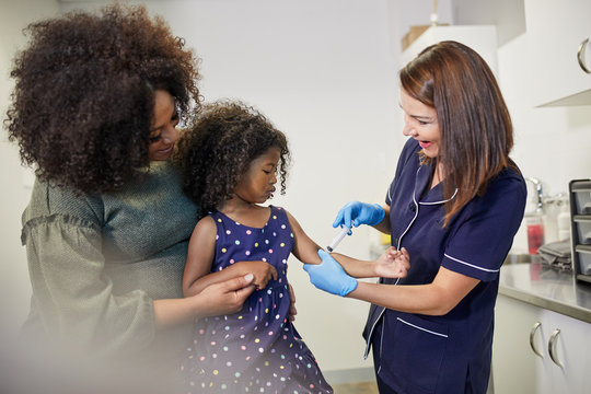 Female pediatrician examining girl in clinic examination room