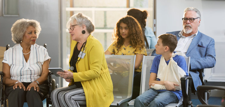Female doctor with digital tablet talking to patient in clinic lobby