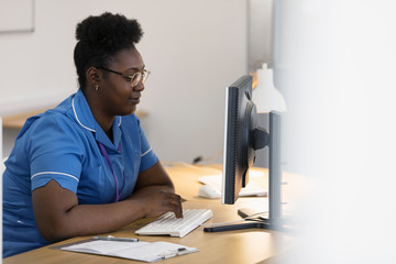 Female nurse working at computer in doctors office