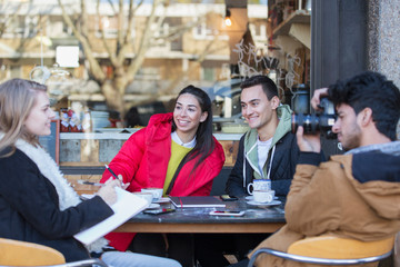Young friends hanging out and studying at sidewalk cafe