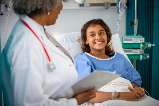 Smiling girl patient talking with doctor in hospital room