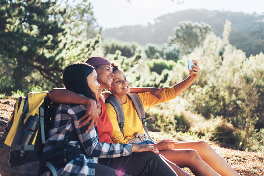 Happy mother and daughters taking selfie, hiking in sunny woods