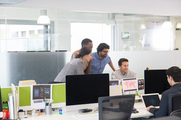 Business people meeting at computer in open plan office