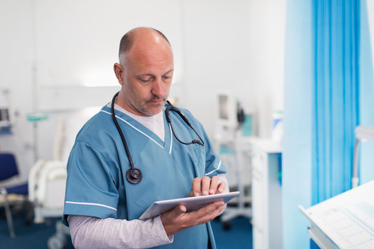Male doctor using digital tablet in hospital room