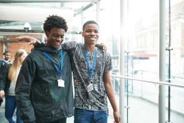Happy high school boy friends walking in corridor