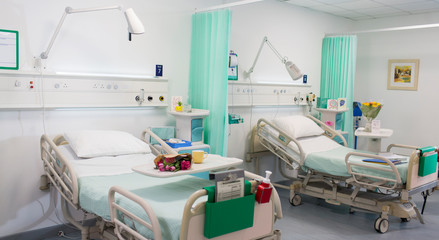 Flowers on trays over hospital beds in vacant hospital ward