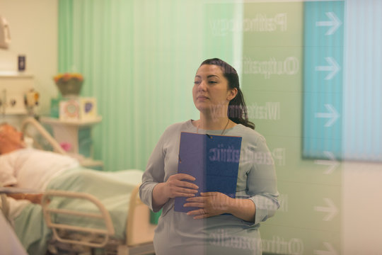 Female doctor with medical chart making rounds in hospital ward