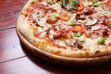 Whole pizza with prosciutto and bacon on wooden background