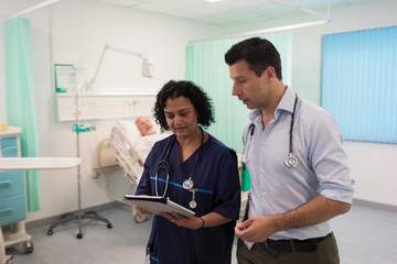 Doctors with digital tablet making rounds, consulting in hospital room