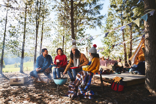 Family cooking at campsite grill in sunny woods