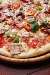 Whole pizza with prosciutto and bacon on wooden background