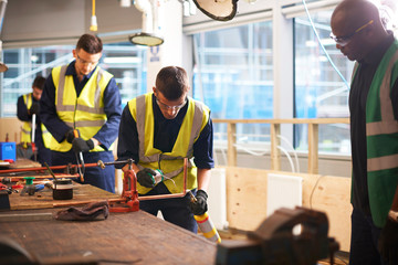 Male instructor watching student welding in workshop