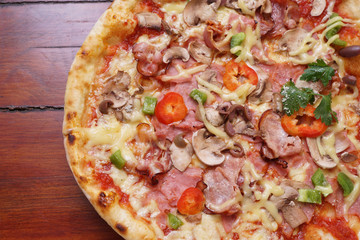 Whole pizza with prosciutto and bacon on wooden background