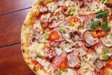 Whole pizza with prosciutto and bacon on wooden background