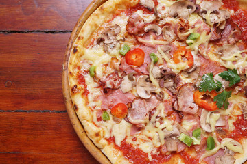 Whole pizza with prosciutto and bacon on wooden background