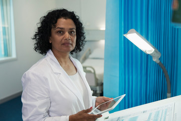 Portrait confident, determined female doctor using digital tablet in hospital room