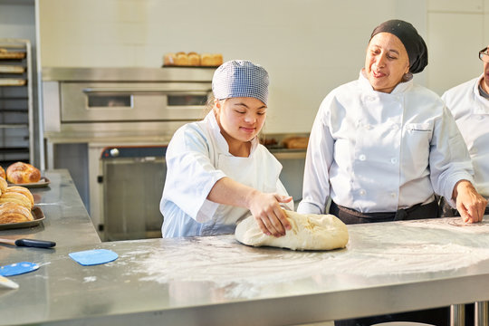Young woman with Down Syndrome learning to bake in kitchen