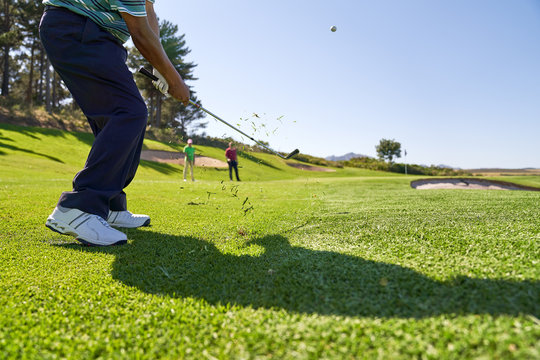 Male golfer taking a shot on sunny golf course