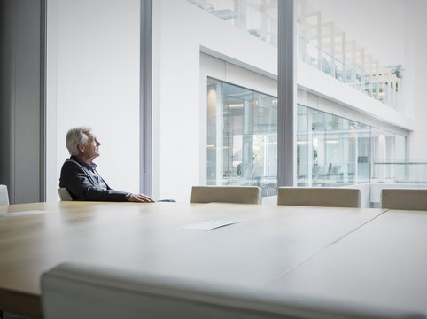 Pensive senior businessman looking out conference room window