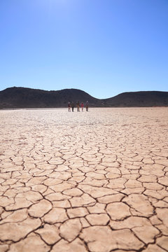 Safari tour group walking along sunny cracked earth South Africa