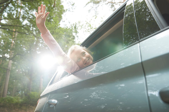 Carefree girl with arm out sunny car window