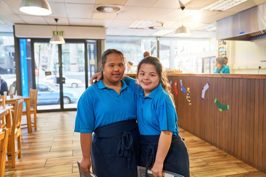Portrait confident young women with Down Syndrome working in cafe