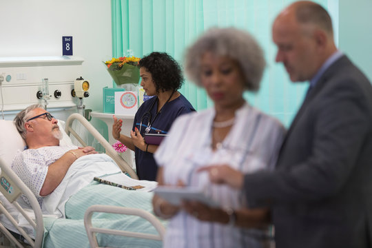 Doctor Making Rounds, Talking With Senior Patient In Hospital Room