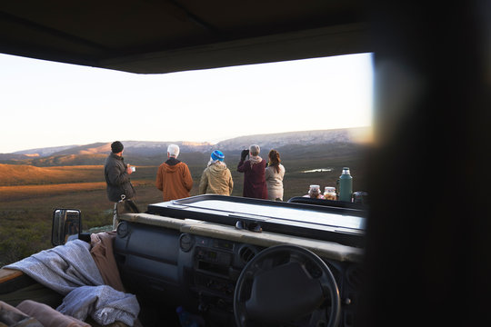 Safari group looking at landscape view outside off-road vehicle