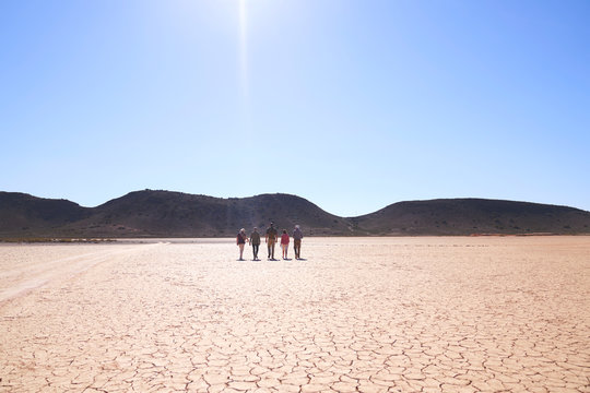 Safari tour group walking along sunny cracked earth South Africa