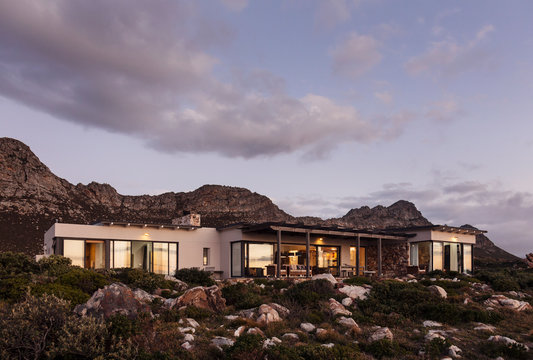 Home showcase exterior on craggy hillside under clouds at dusk