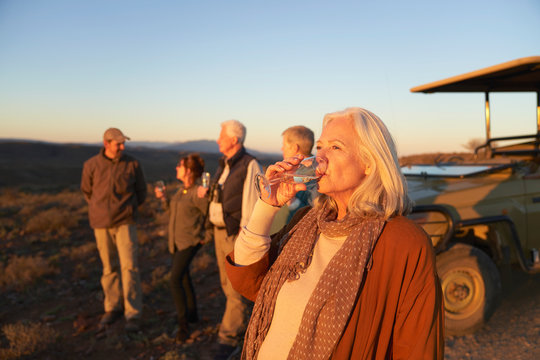 Senior woman on safari drinking champagne at sunset