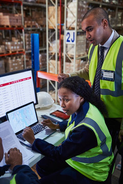 Managers meeting at laptop and computer in distribution warehouse