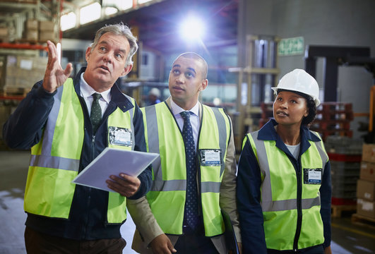 Managers and worker talking looking up in distribution warehouse