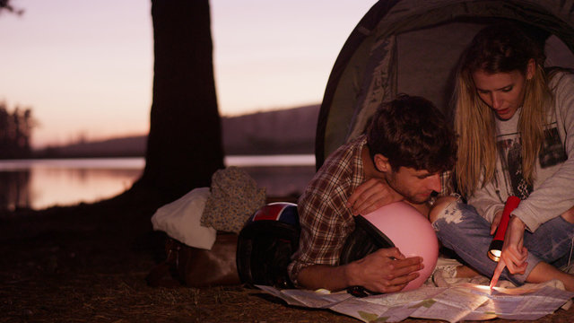 Young couple looking at maps in camping tent