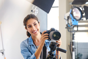 Smiling female photographer behind camera in studio